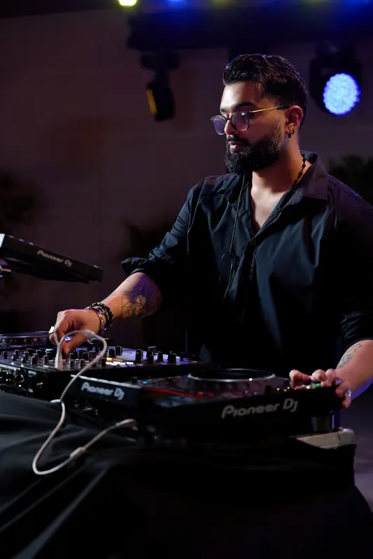 Just AMN, Dubai-based open-format DJ, mixing on Pioneer DJ decks under blue stage lights